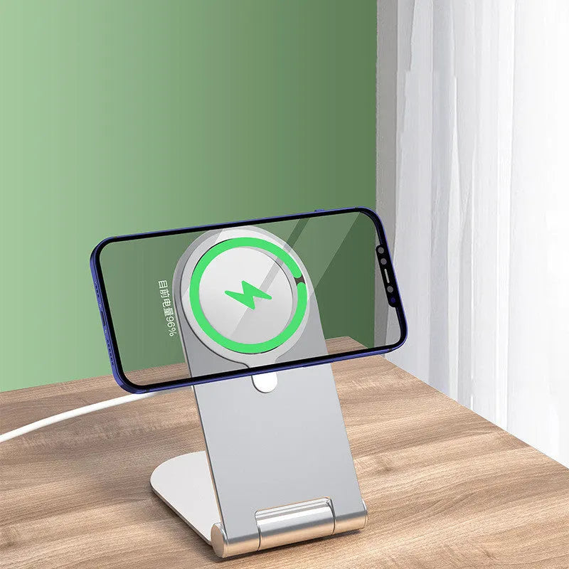 Silver vertical adjustable magnetic phone bracket for iPhone 12 on a table.