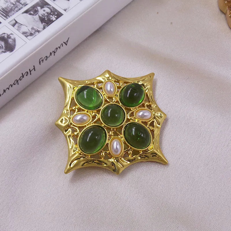 Close-up of a medieval-style baroque cross brooch with crystal decoration on a metal base.