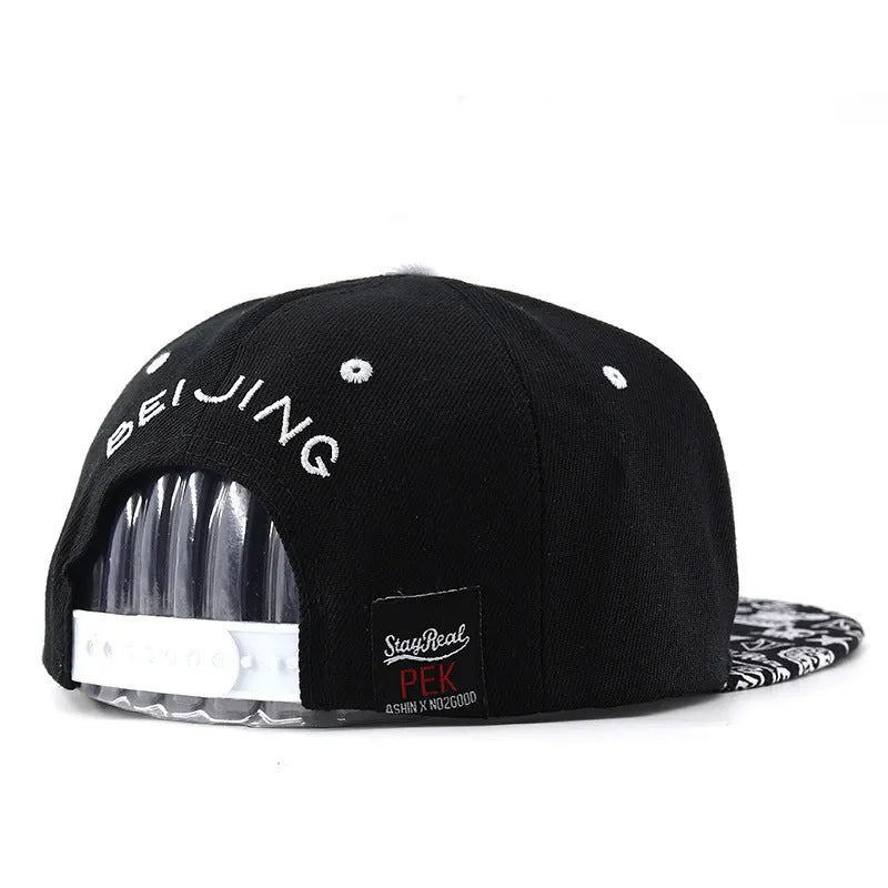 Cotton baseball cap with embroidered letters in black or white, showing adjustable strap.