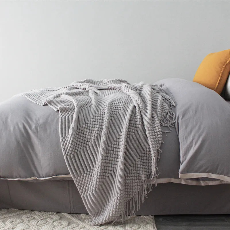 Small dark grey polyester nap blanket folded, showing its size of 127 cm by 170 cm.