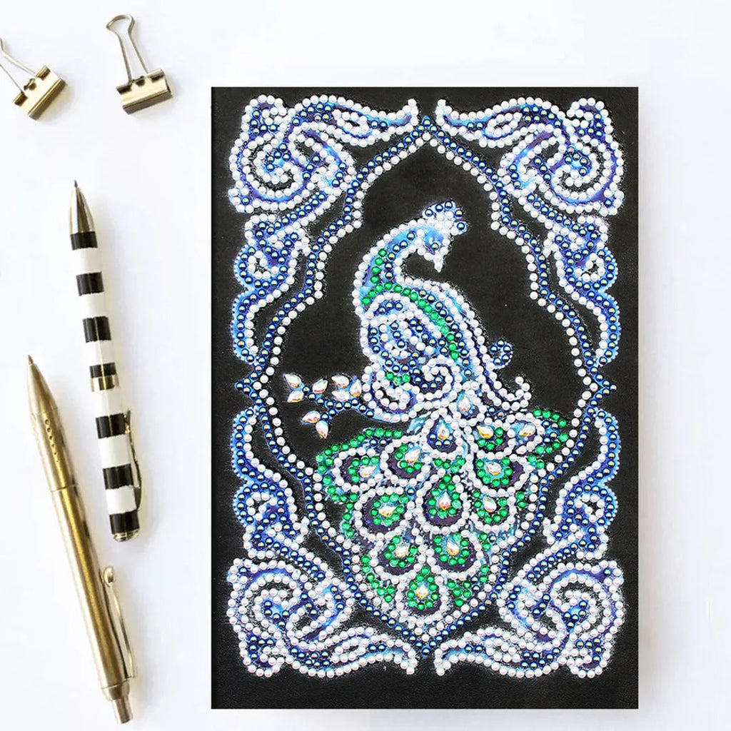 Black A5 notebook with a peacock design made from shaped and bright diamond painting drills.