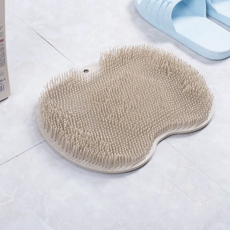 Orange silicone bath massage brush mat with suction cups on a bathroom floor