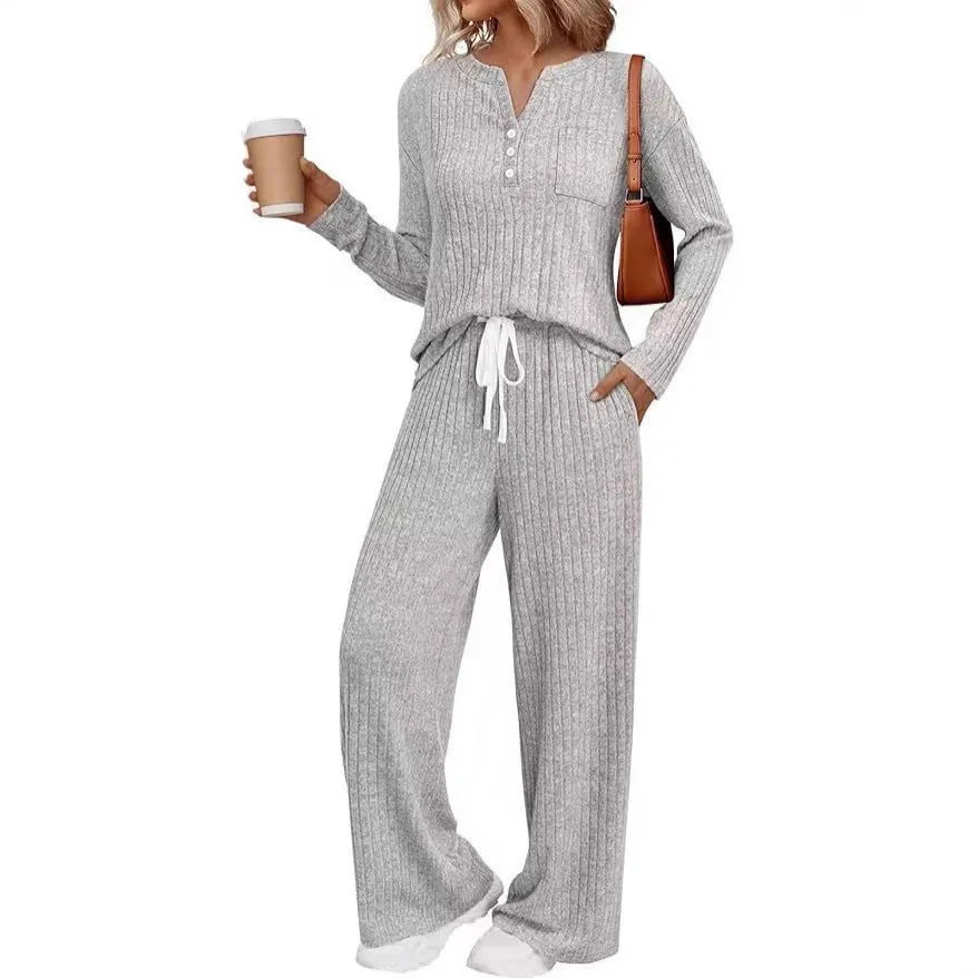 A person wearing a striped V-neck knit long coat with lace-up details and pockets, paired with matching pants.