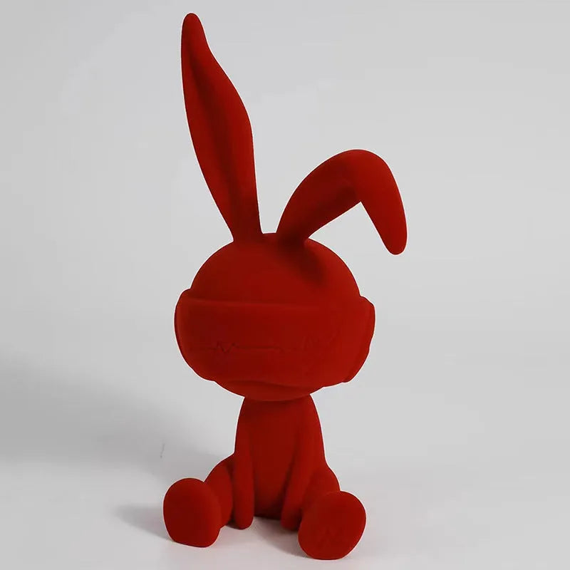 Suede blindfold rabbit resin table ornament in blue, green, or red colour on a shelf.