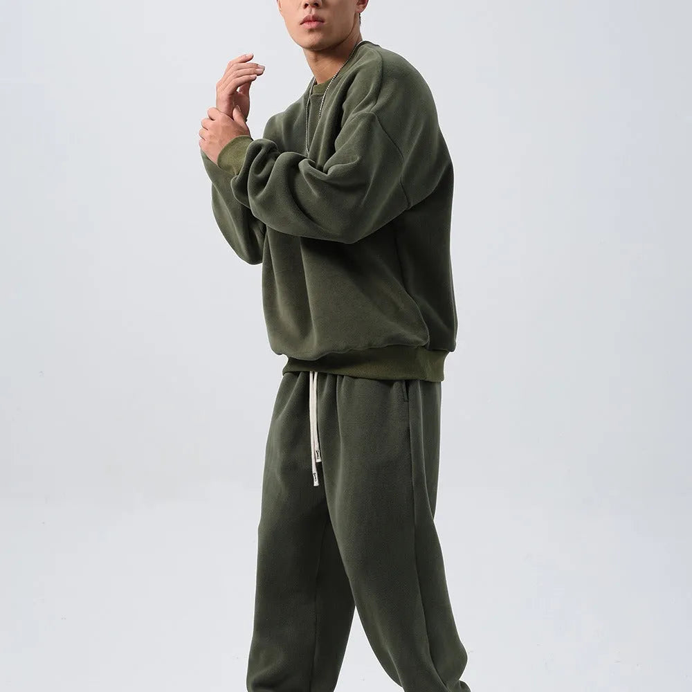 Man wearing a loose black polar fleece sports suit with a crew neck coat and trousers.