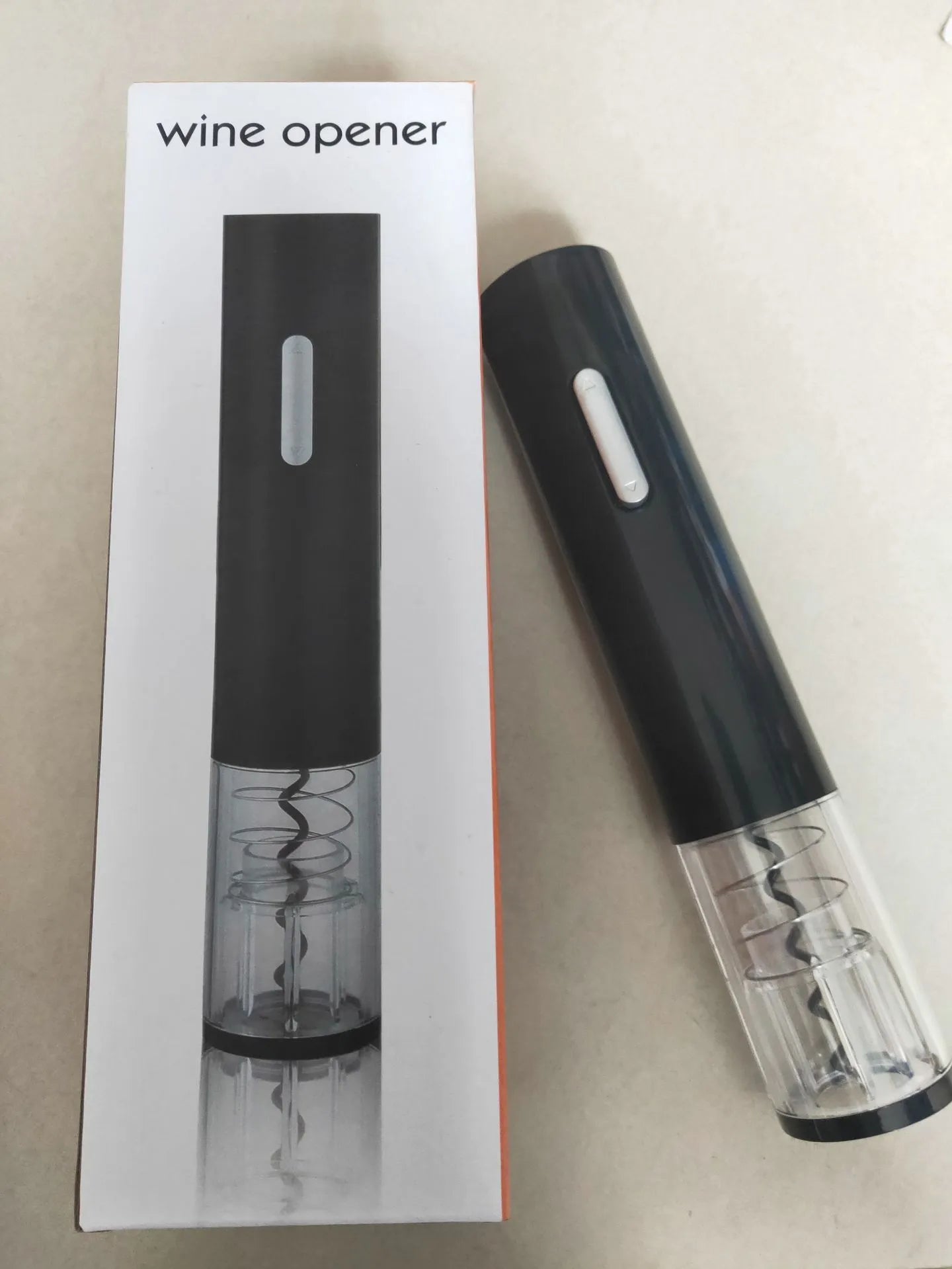 Black, red, and white electric wine bottle opener with foil cutter on a kitchen counter
