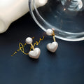 Close-up of simple heart-shaped alloy stud earrings with inlaid artificial gemstones.