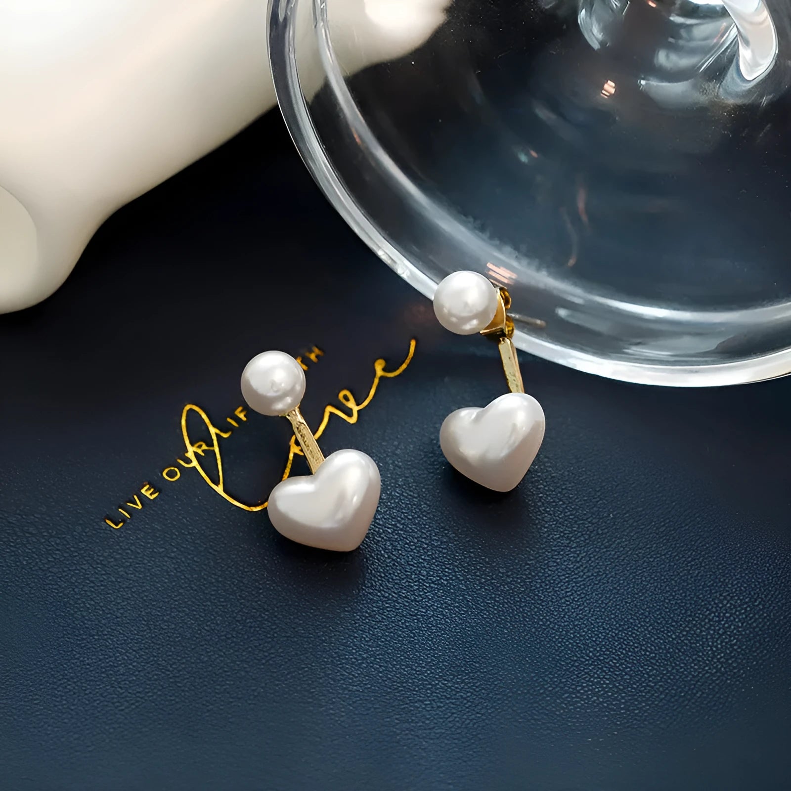 Close-up of simple heart-shaped alloy stud earrings with inlaid artificial gemstones.