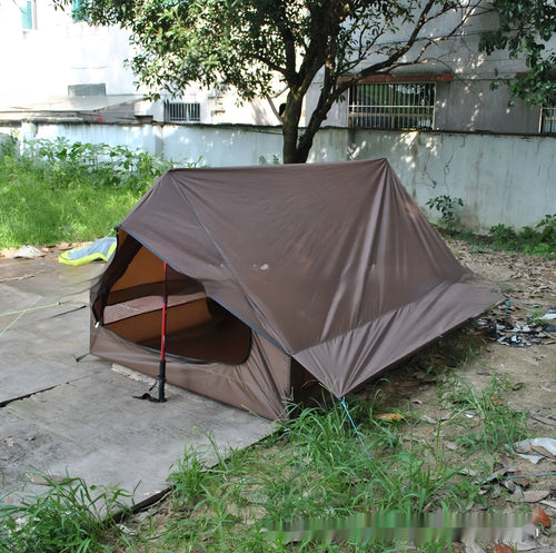 Brown A-line cabin tent pitched with hiking poles as structural support showing spacious interior for 2-3 people