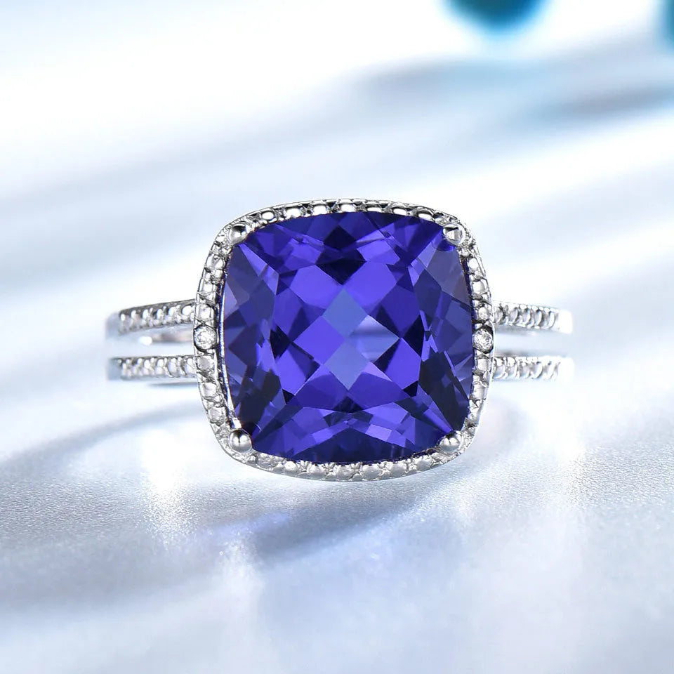 Women's sterling silver ring with oval blue Tanzanite gemstone on a finger.