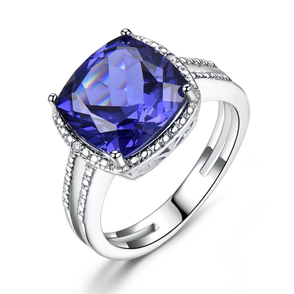 Women's sterling silver ring with oval blue Tanzanite gemstone on a finger.