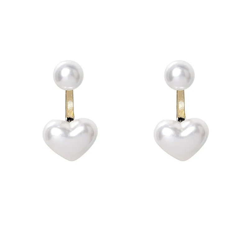 Close-up of simple heart-shaped alloy stud earrings with inlaid artificial gemstones.