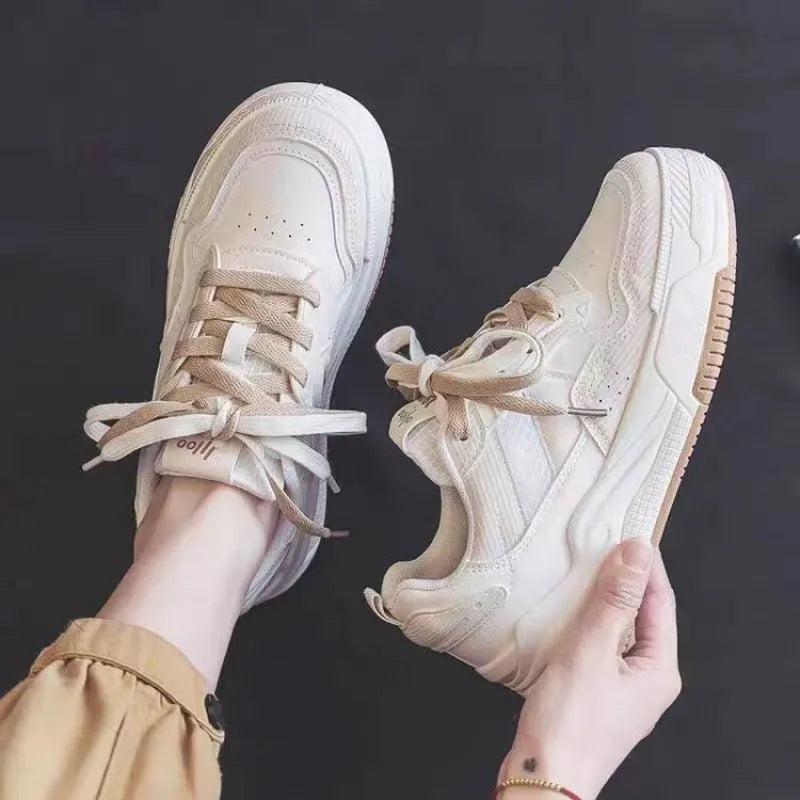 Women's pink and white low top imitation leather sneaker with rubber sole on a neutral background.