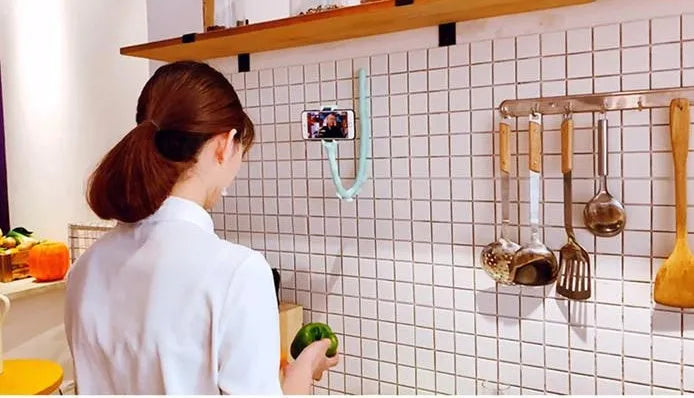 Flexible black suction cup phone holder bent into position on a desktop