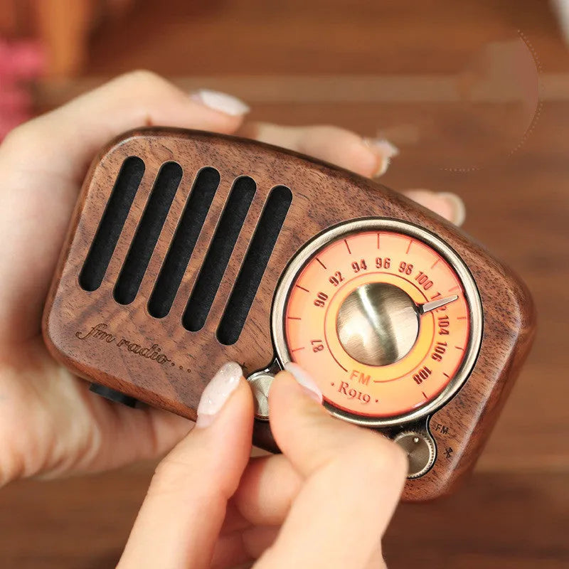 Compact retro wooden wireless Bluetooth speaker in cherry wood finish on a wooden table