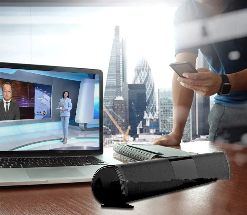 Tall black Bluetooth sound bar speaker with remote control on a wooden surface