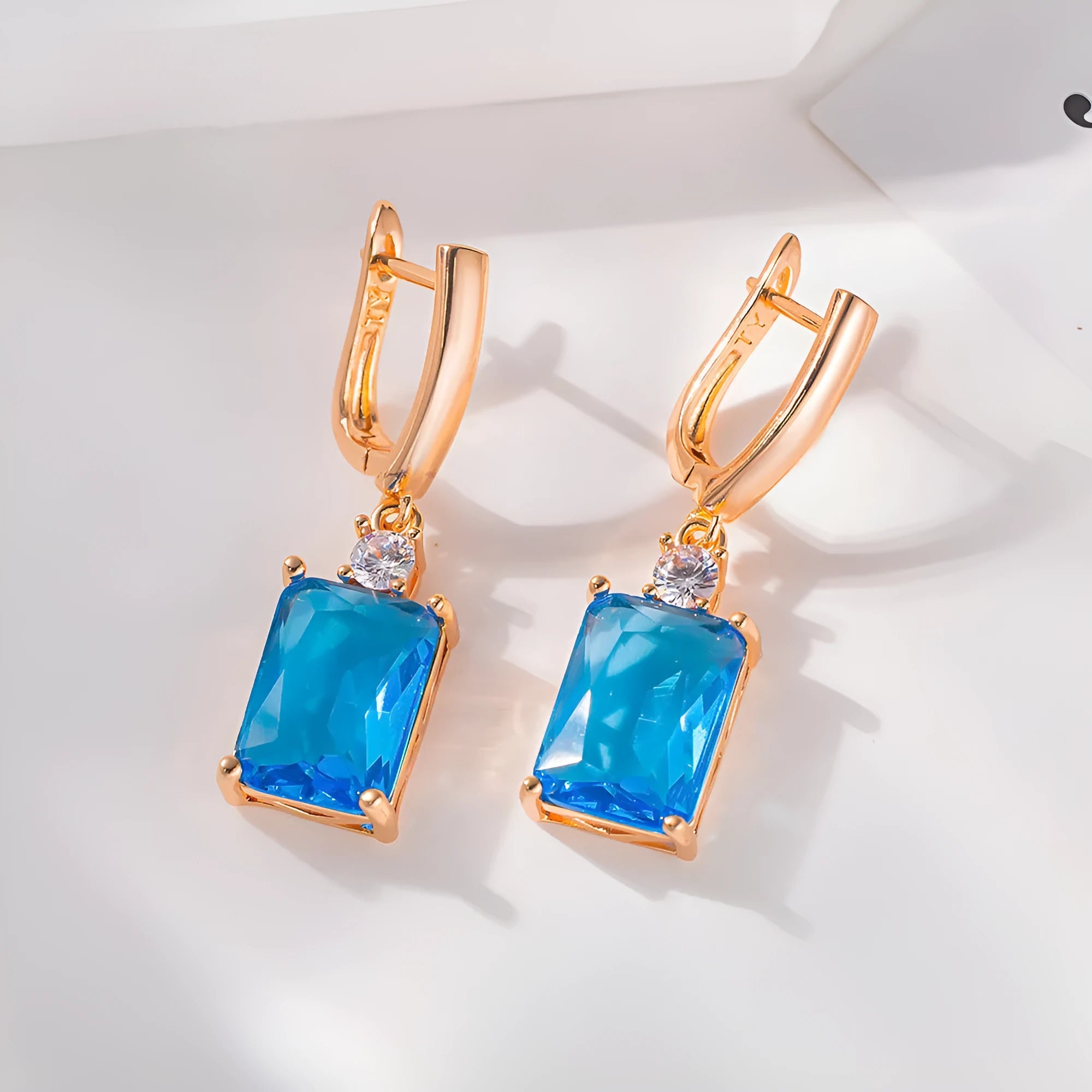 A pair of square-shaped gold-coloured geometric earrings on a white background.