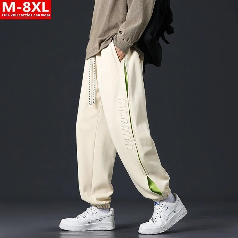 Men's loose grey green cotton trousers with ankle banding and stitching print detail on the leg.