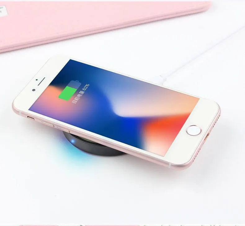 Square Qi wireless phone charging pad in multiple colours on a wooden surface.