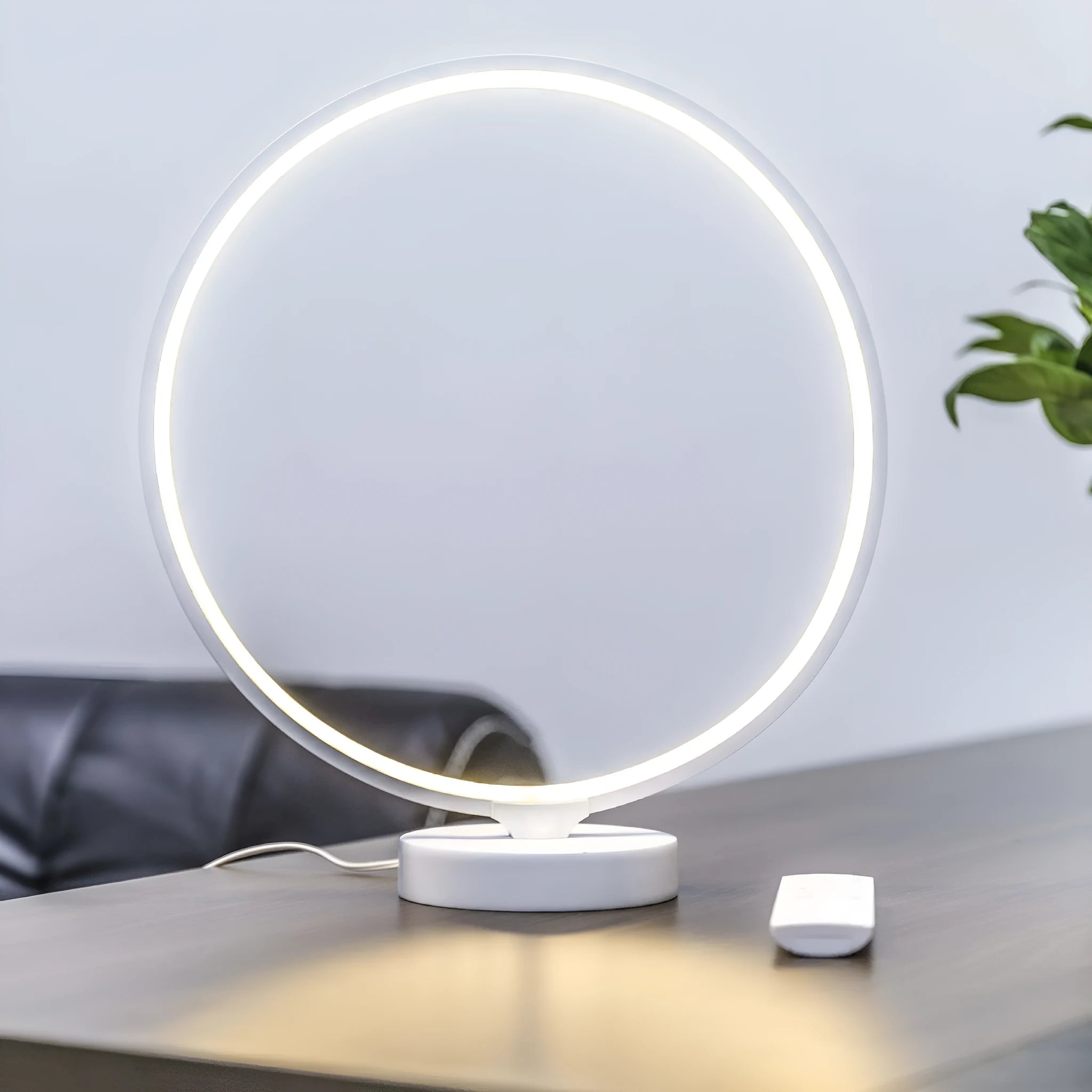 White Full Moon Table Lamp with remote control on a wooden surface, showing its spherical silicone and aluminium design.