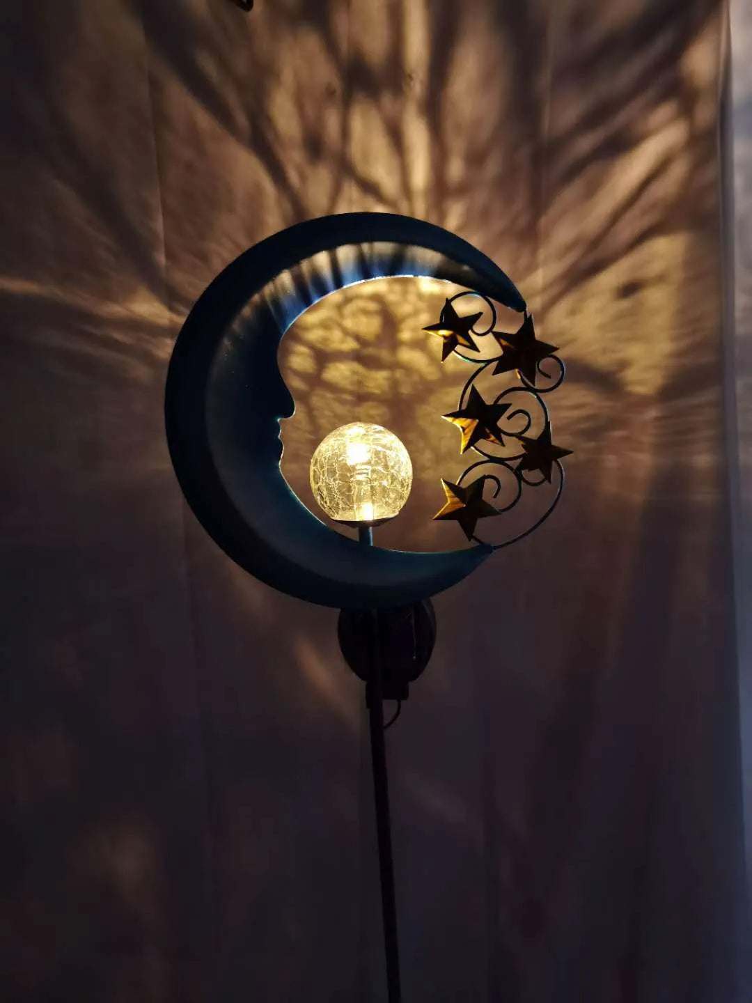 Blue moon-shaped solar garden light with wrought iron metal frame and crack glass ball.