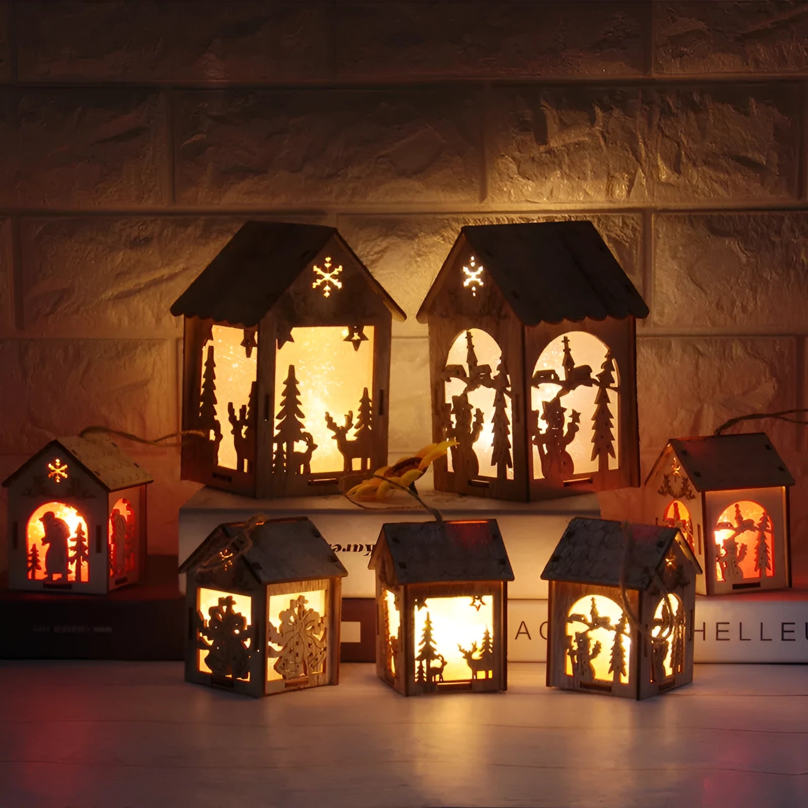 Three wooden Christmas decorations: small log bell and two wooden houses with Father Christmas and snowman designs