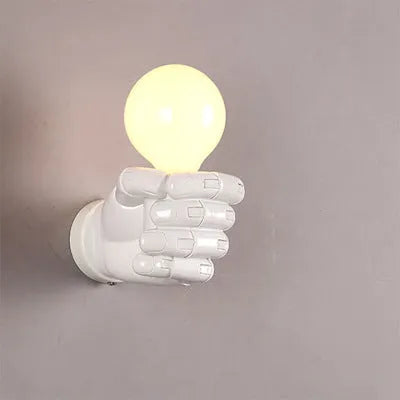 Decorative resin wall lamp sculpted as a clenched fist, available in black, white, and wood grain finishes.