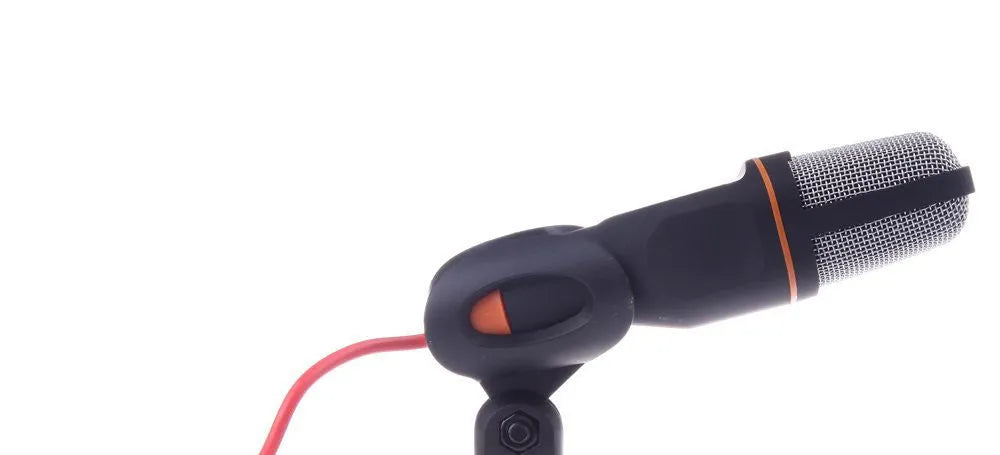 Black wired PC microphone with a long cable and a detached metal clip holder on a desk.