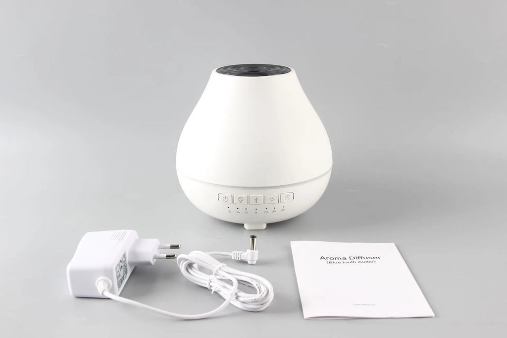 Round white Bluetooth humidifier and aroma diffuser with night light on a surface.