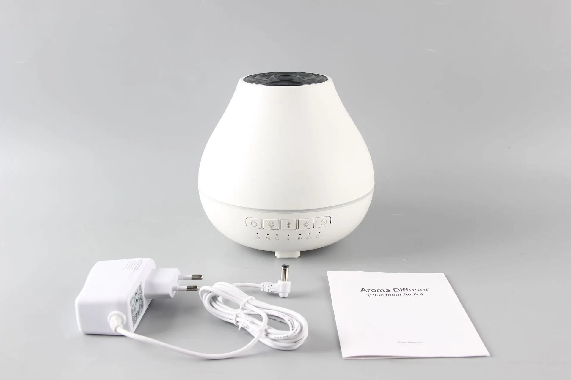Round white Bluetooth humidifier and aroma diffuser with night light on a surface.