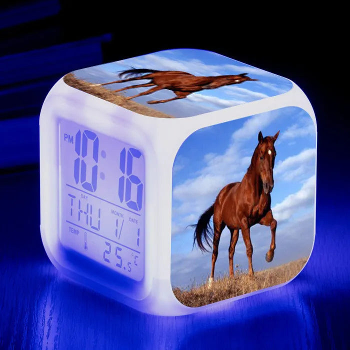 Small square cartoon-style LED alarm clock showing time and temperature, in one of 15 available colour variants.