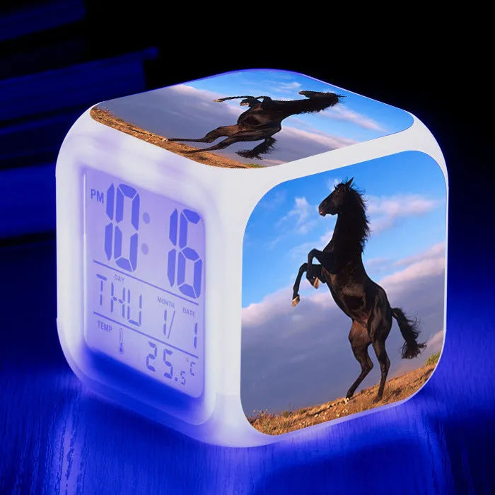 Small square cartoon-style LED alarm clock showing time and temperature, in one of 15 available colour variants.