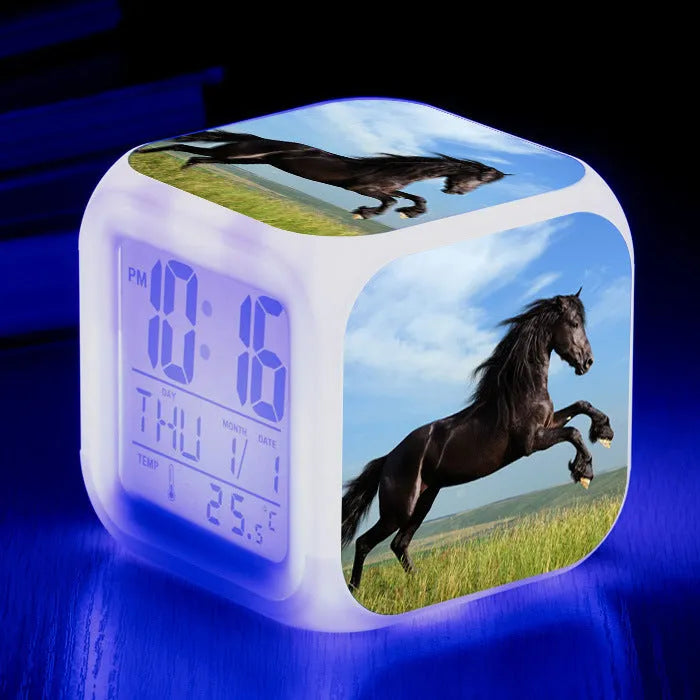 Small square cartoon-style LED alarm clock showing time and temperature, in one of 15 available colour variants.