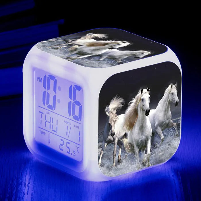 Small square cartoon-style LED alarm clock showing time and temperature, in one of 15 available colour variants.