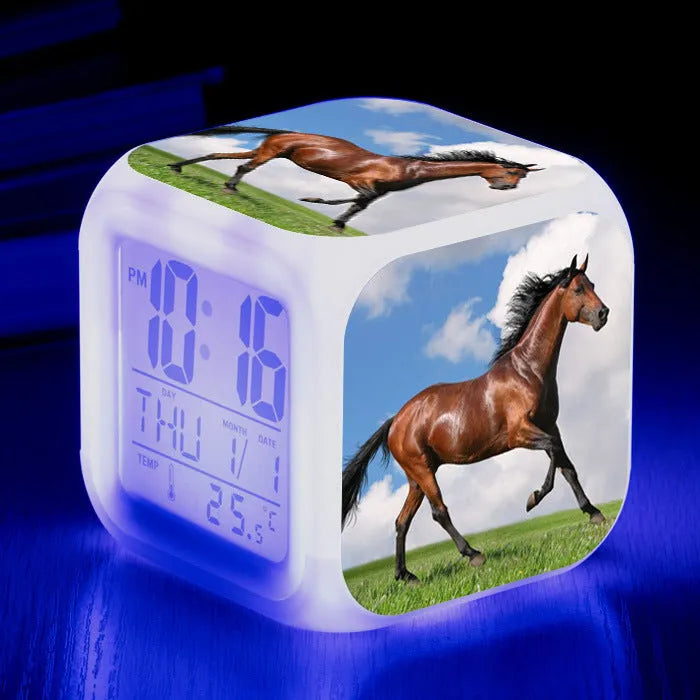 Small square cartoon-style LED alarm clock showing time and temperature, in one of 15 available colour variants.