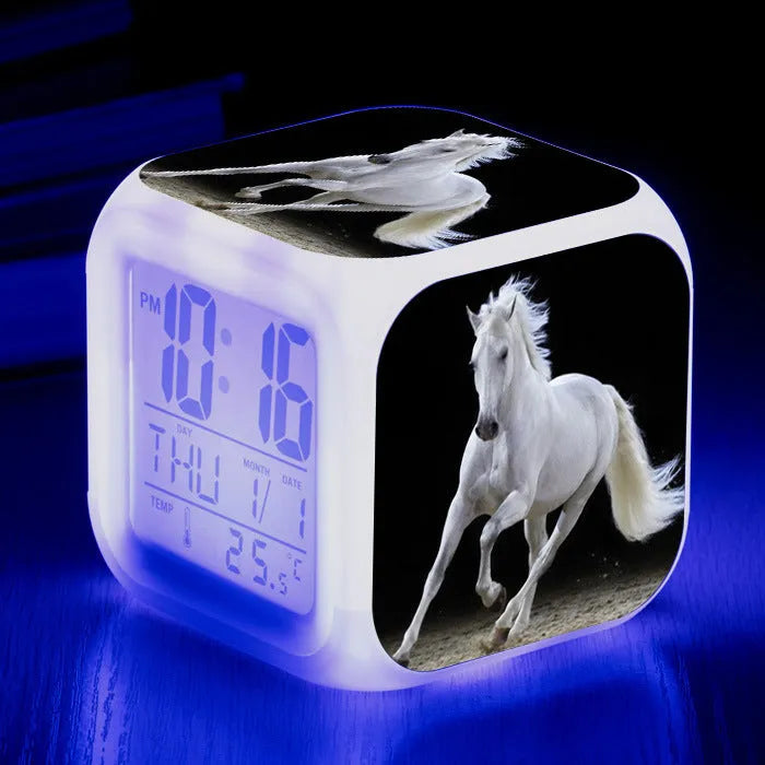 Small square cartoon-style LED alarm clock showing time and temperature, in one of 15 available colour variants.