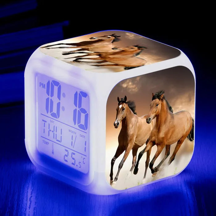 Small square cartoon-style LED alarm clock showing time and temperature, in one of 15 available colour variants.