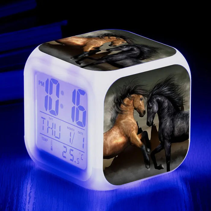 Small square cartoon-style LED alarm clock showing time and temperature, in one of 15 available colour variants.
