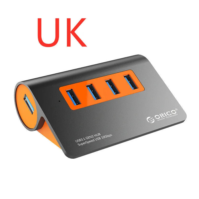 Dark grey aluminium USB-C hub with four USB 3.1 ports, orange trim, external power input, and a separate cable.