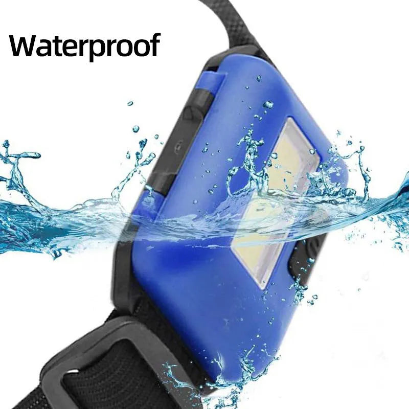 Compact black, blue, or red outdoor LED headlamp with adjustable strap on a grey background