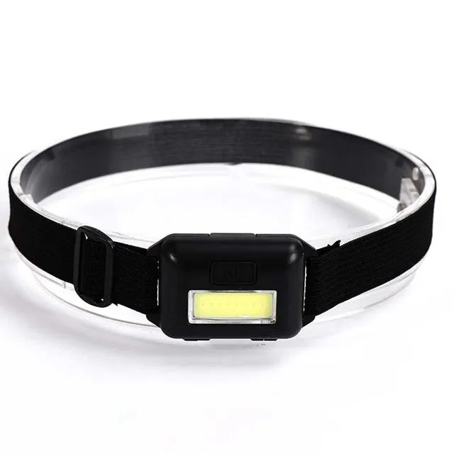 Compact black, blue, or red outdoor LED headlamp with adjustable strap on a grey background