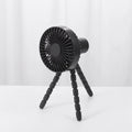 Black flexible tripod USB desktop fan with automatic head shake, shown on a desk next to a laptop.