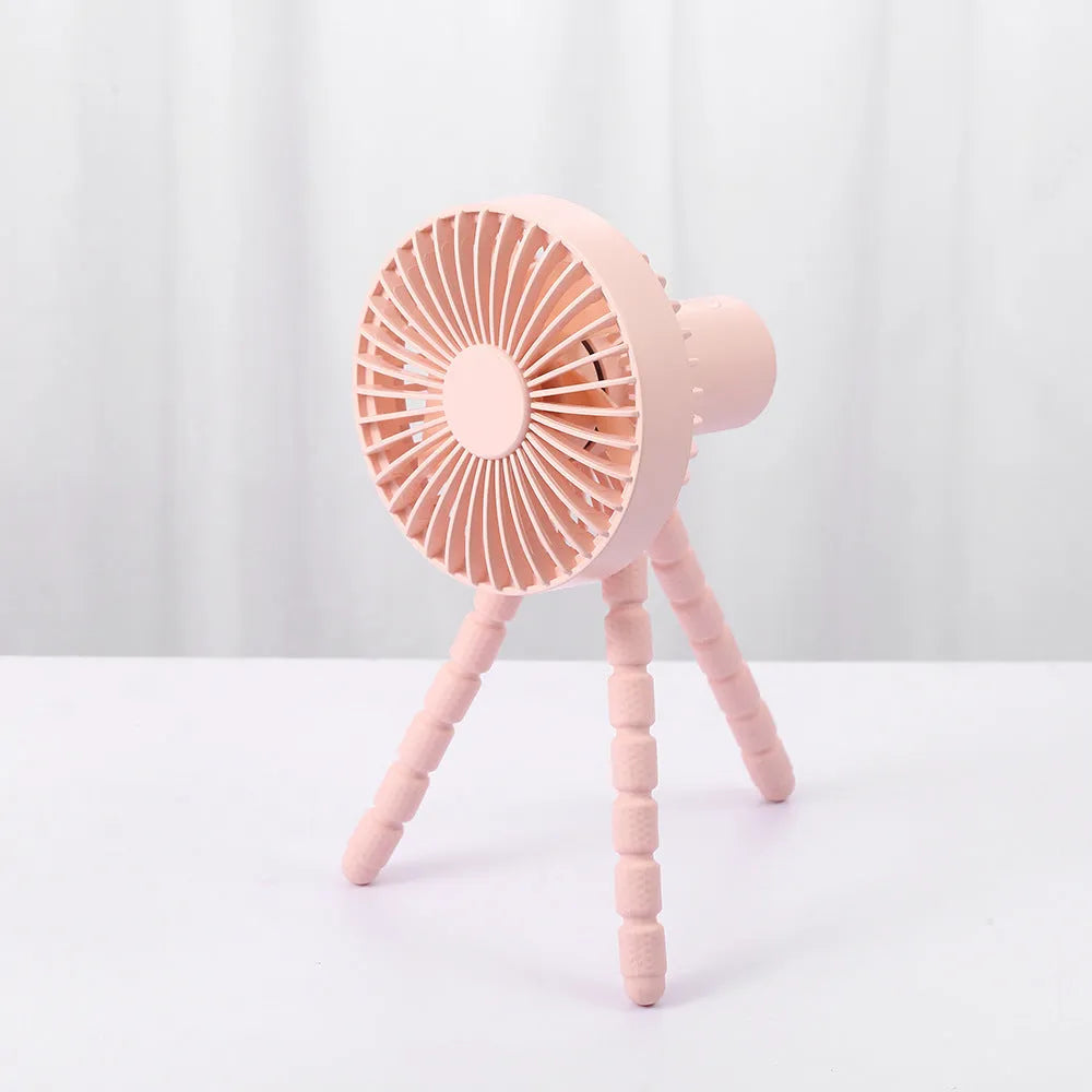 Black flexible tripod USB desktop fan with automatic head shake, shown on a desk next to a laptop.