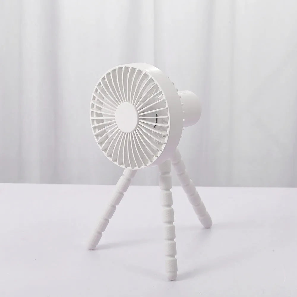 Black flexible tripod USB desktop fan with automatic head shake, shown on a desk next to a laptop.
