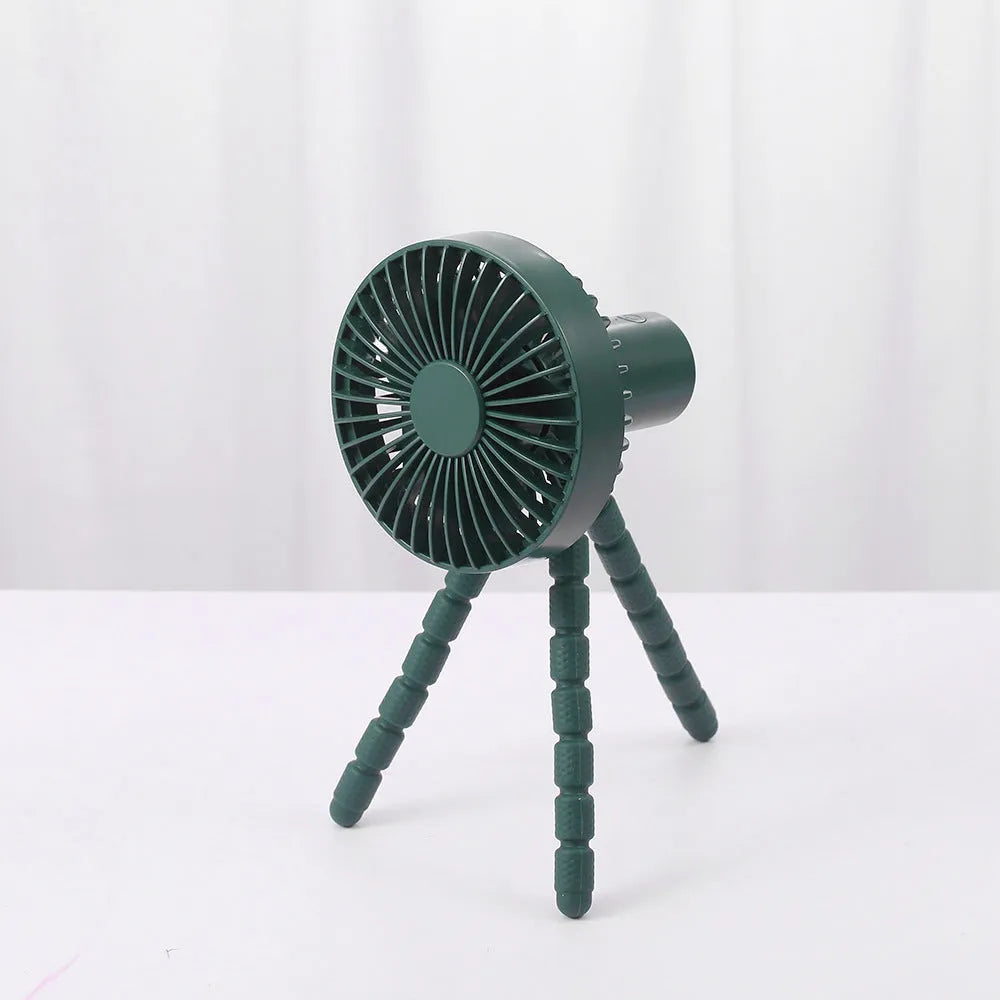 Black flexible tripod USB desktop fan with automatic head shake, shown on a desk next to a laptop.