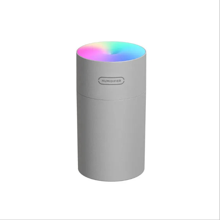Pink USB desktop humidifier with coloured lights and water tank on a wooden desk