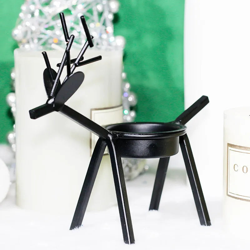 Black iron Christmas candlestick holder with decorative elk design on a table.