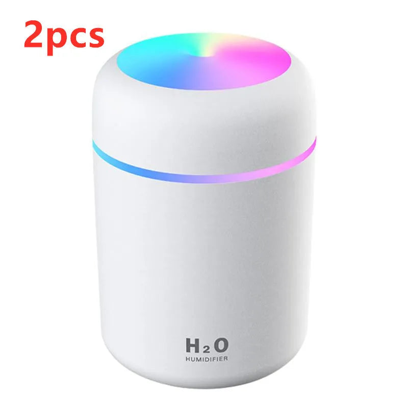 Pink USB desktop humidifier with coloured lights and water tank on a wooden desk