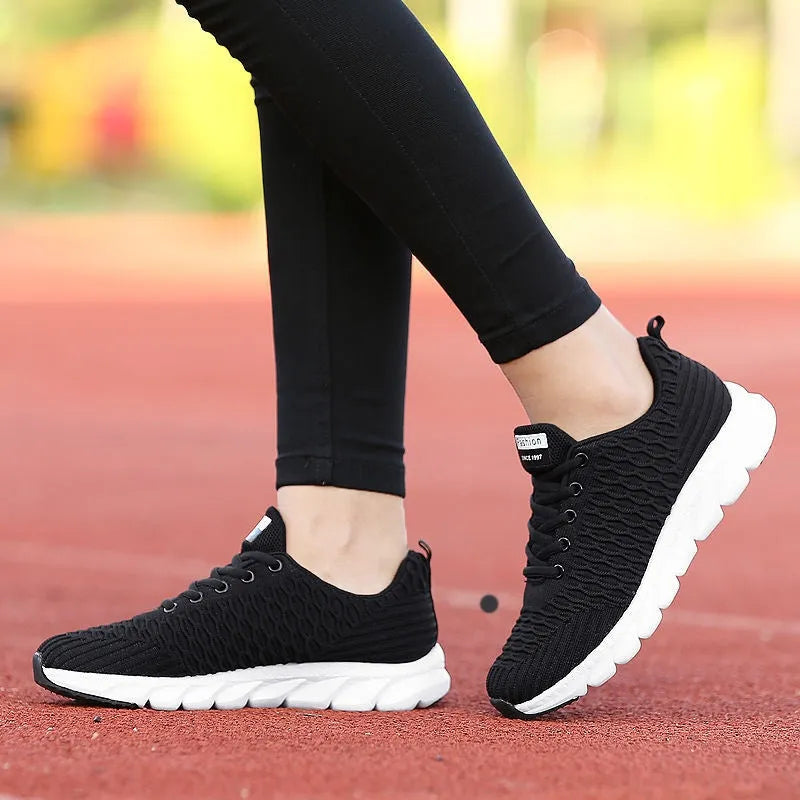 Women's running shoes in black, pink and white colours showing fly weave upper and durable outsole