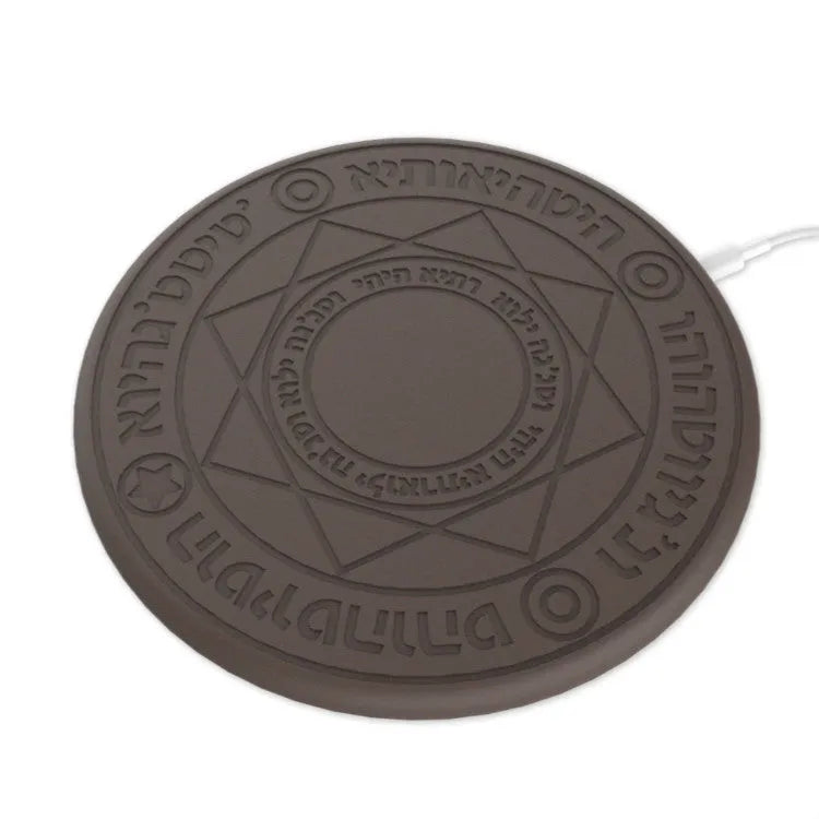 Black 10W fast wireless phone charger with glowing magic array pattern on a desk.
